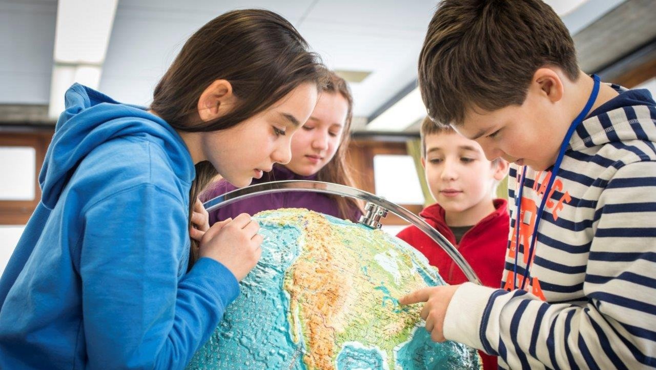 Schüler beugen sich um einen Globus