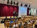 Bild der Schülersprecher auf der Bühne der Aula. Sie zeigen eine Präsentation